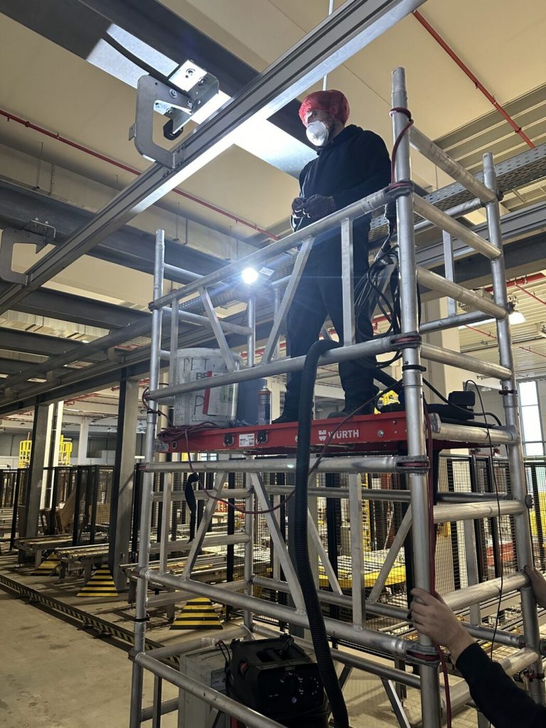 Reinigung der EHB-Schiene vom Rollgerüst aus in der Produktionshalle