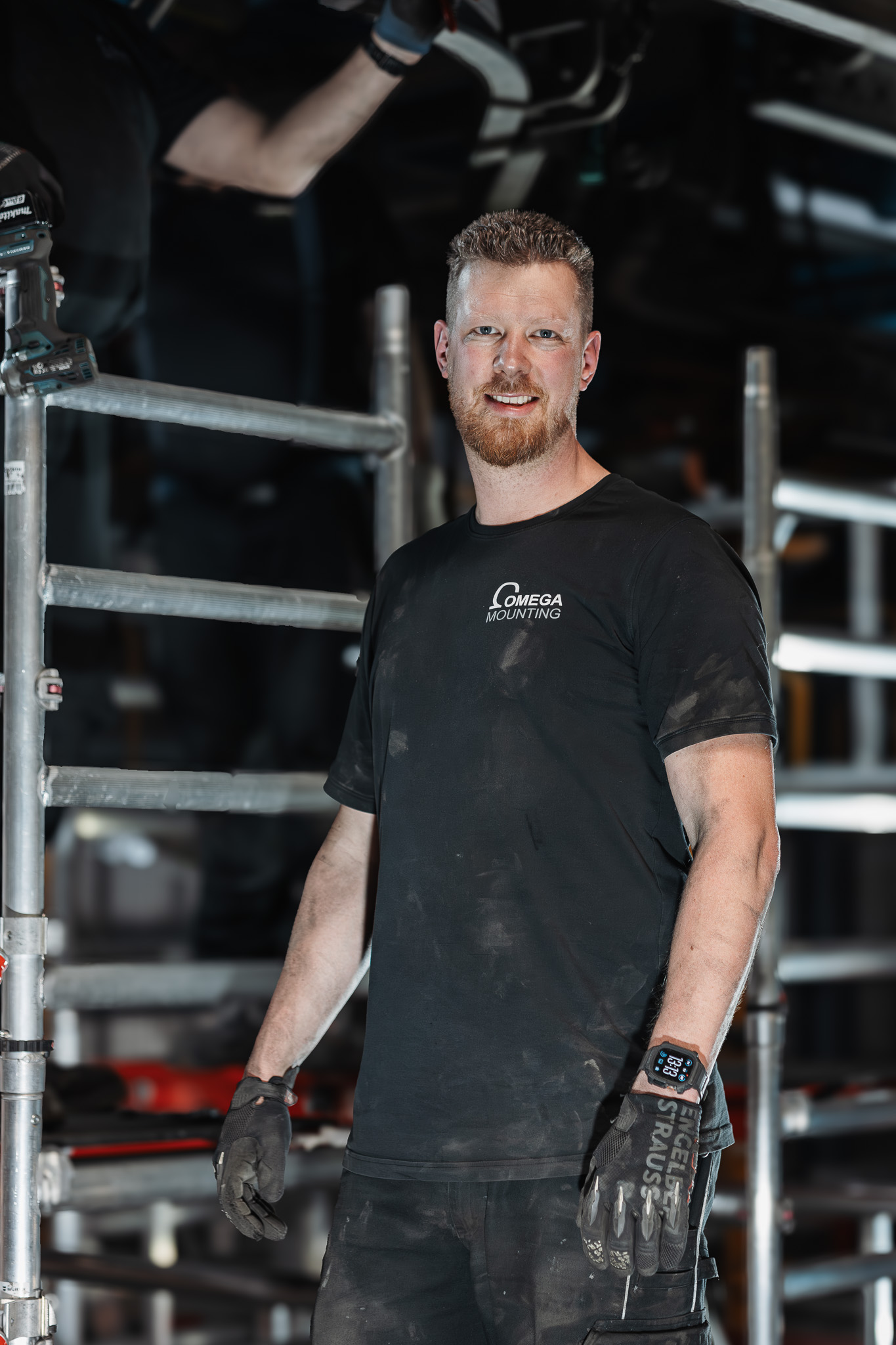 Tobias Schott, Geschäftsführer der Omega Mounting GmbH, im Arbeitsshirt vor einem Fahrgerüst im Einsatz