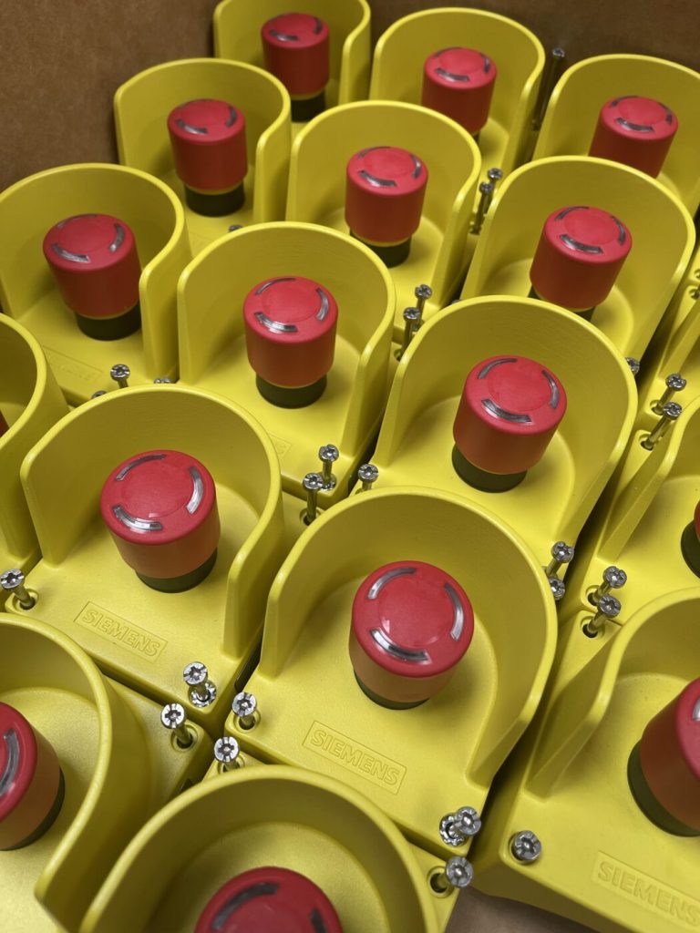 Gelbe Not-Aus-Taster mit rotem Schlagknopf vor der Montage