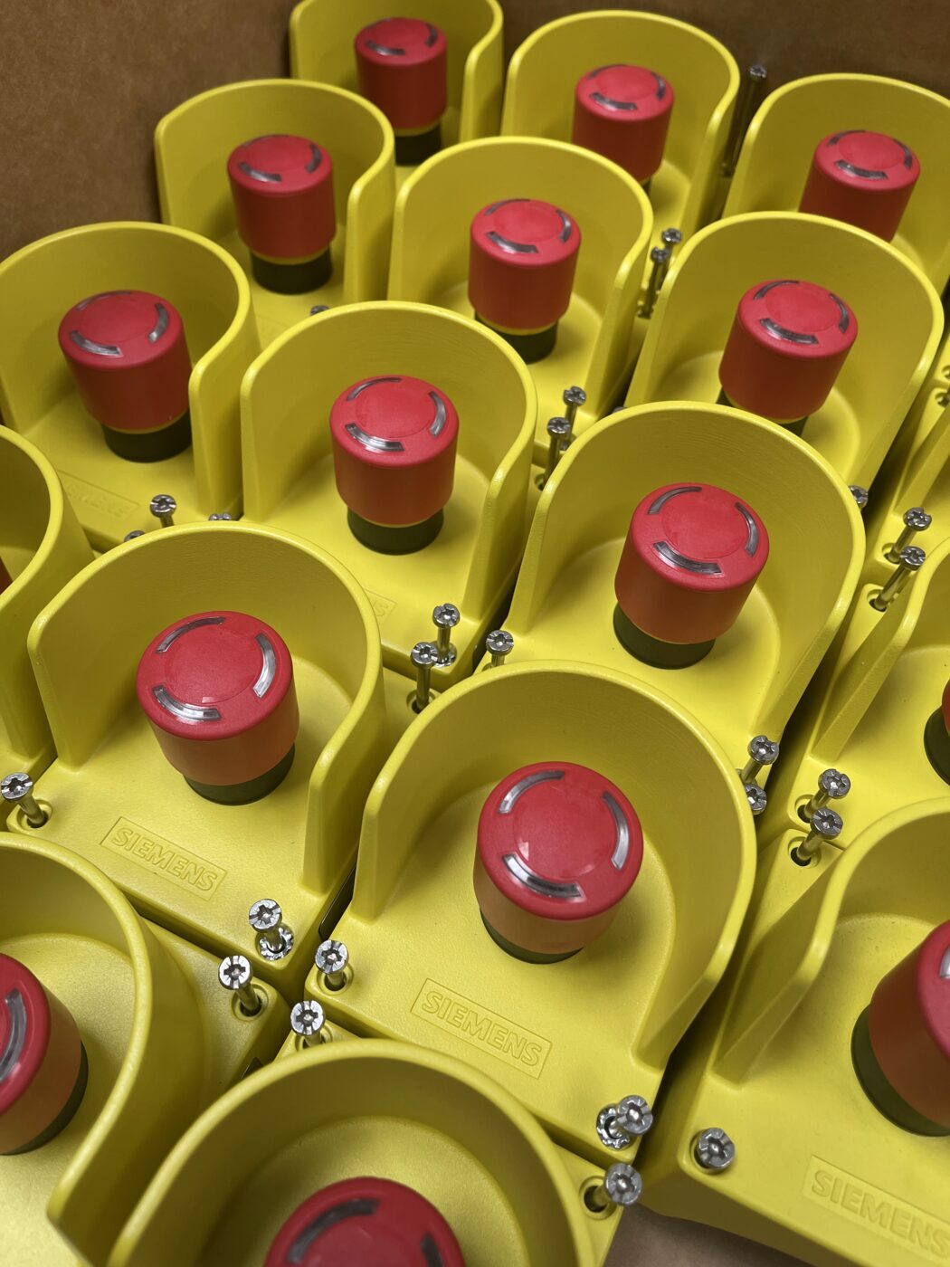 Gelbe Not-Aus-Taster mit rotem Schlagknopf vor der Montage