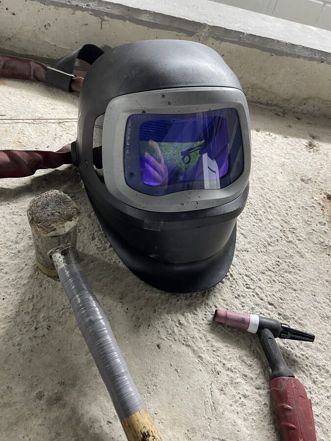 WIG-Schweißhelm und Brenner beim Schweißen der Ölwanne im Kellerraum