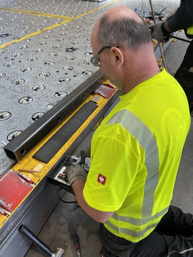 Montage des Rammschutz-Vierkantrohrs vor den Abzugsrollen an der Kante des Loading Docks