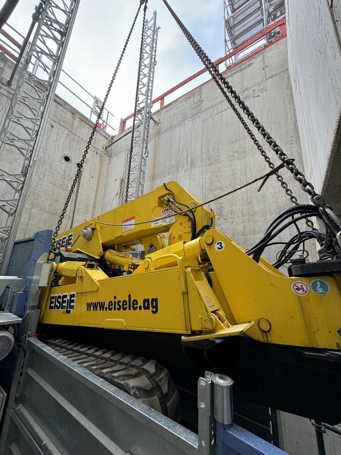 Der Spinnenkran am Kettengehänge unmittelbar neben dem Bauaufzug