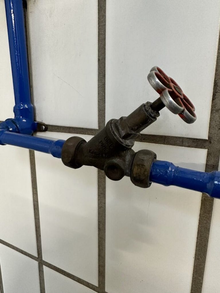 Wasserleitung mit Absperrventil an der Wand der Waschhalle