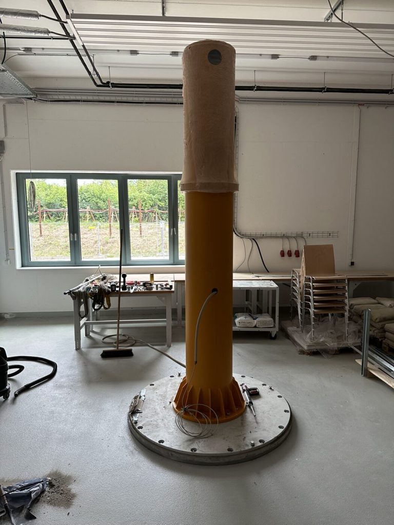 Aufgestellte Kransäule in der Werkstatt, noch ohne Ausleger, im Hintergrund die montierten Arbeitsplätze