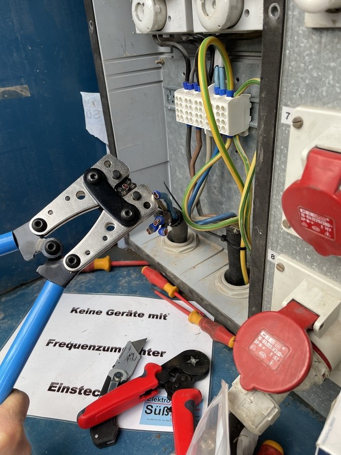 Arbeit im Inneren eines Baustromverteilers mit Aderendhülsen und Zange am Klemmenblock