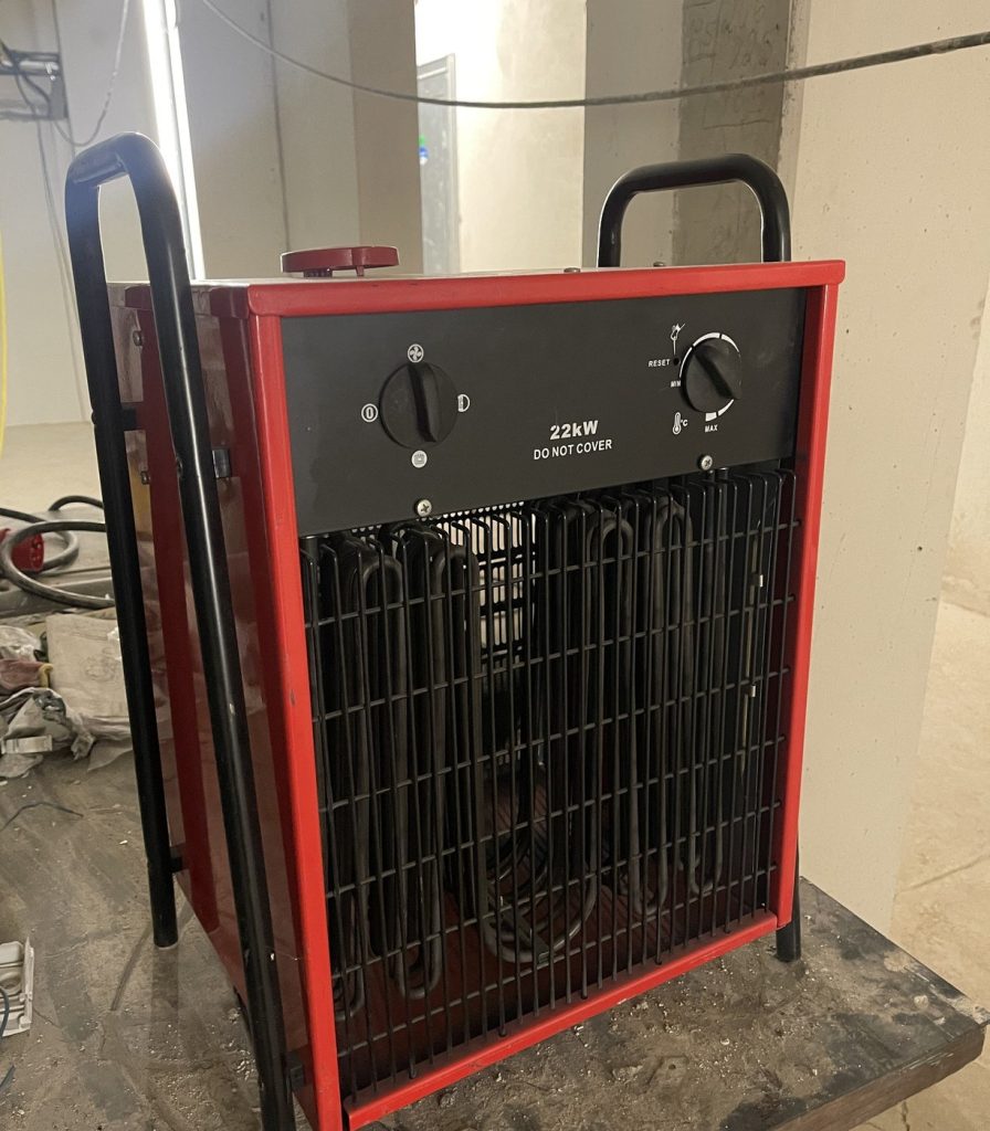 Elektrischer Bauheizer mit 22 kW Heizleistung im Rohbau, angeschlossen über Starkstrom für Trocknung und Winterbaustelle