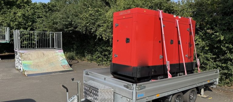Schallgedämmtes 110-kVA-Stromaggregat auf einem Tandem-Anhänger, gesichert mit Spanngurten, bereit zur Auslieferung auf die Baustelle