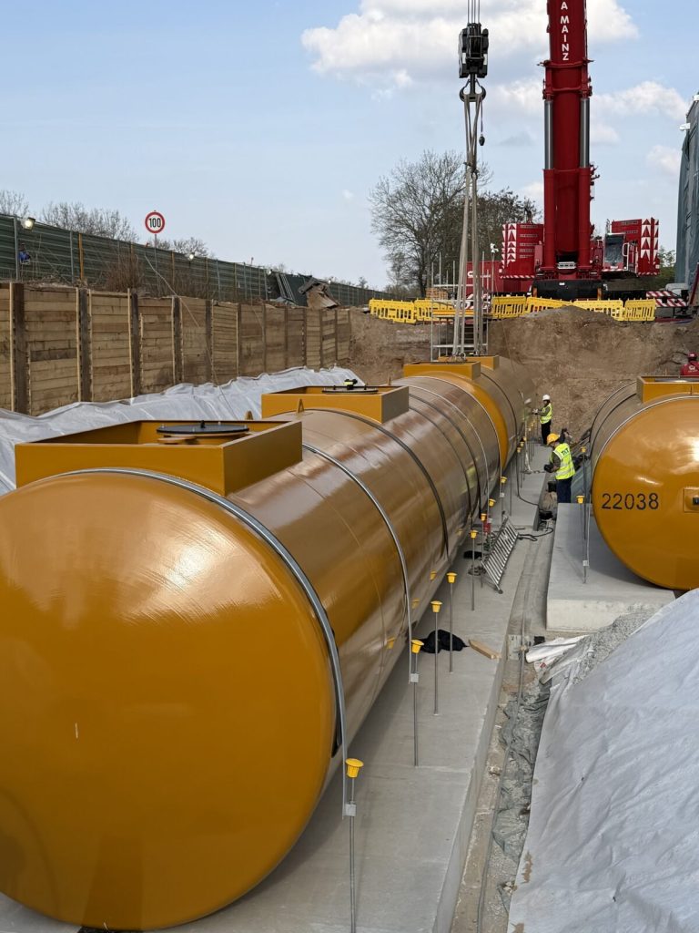 Reihe der abgesetzten Dieseltanks auf ihren Auflagern in der ausgekleideten Grube