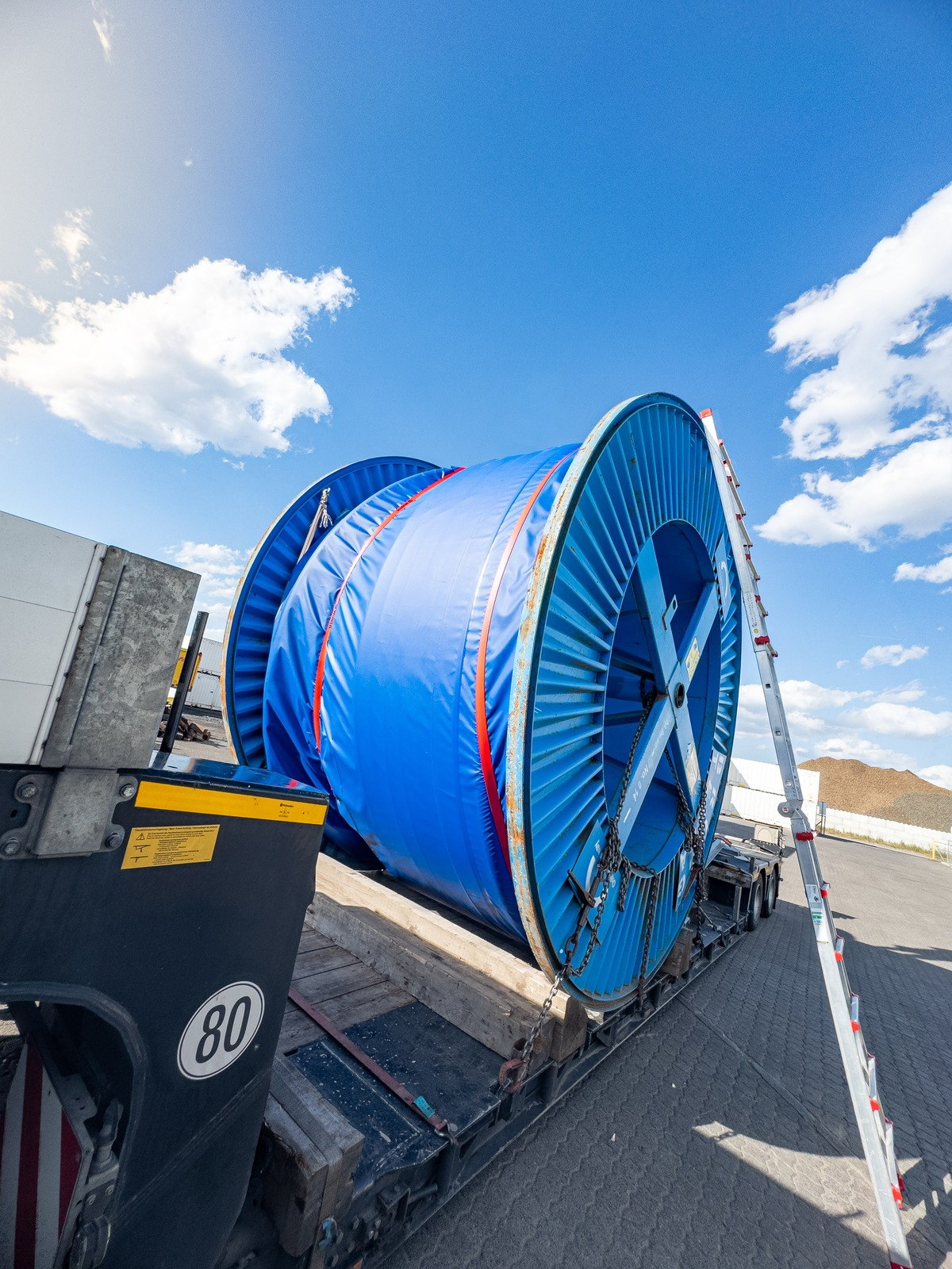 Kabeltrommel mit UV-Schutzplane verzurrt auf dem Tieflader im Hafen Aschaffenburg