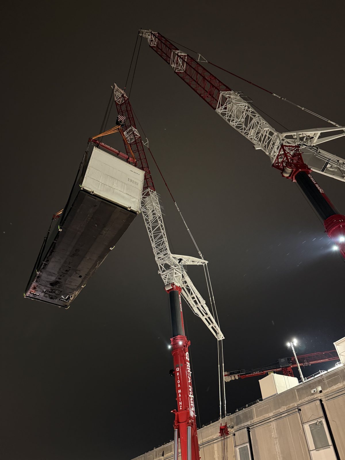 Tandemhub mit zwei Kranen: Containerlösung einer Netzersatzanlage über dem Gebäude