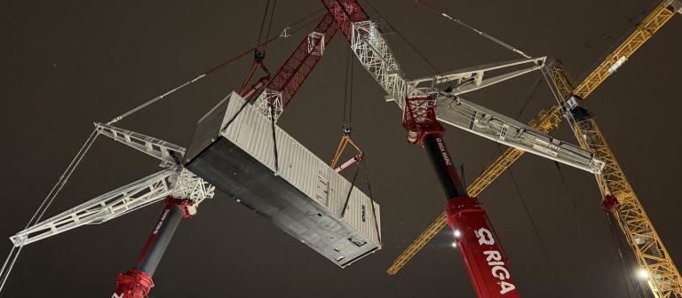 Tandemhub bei Nacht: zwei Autokrane heben eine Netzersatzanlage als Containerlösung über ein Rechenzentrum im Raum Frankfurt