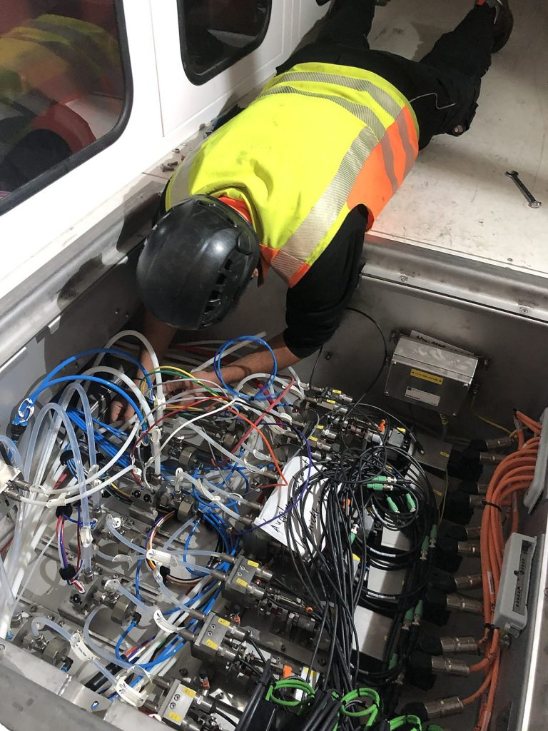 Monteur verschlaucht Ventilblöcke und Leitungen beim Neubau einer Lackieranlage in Italien